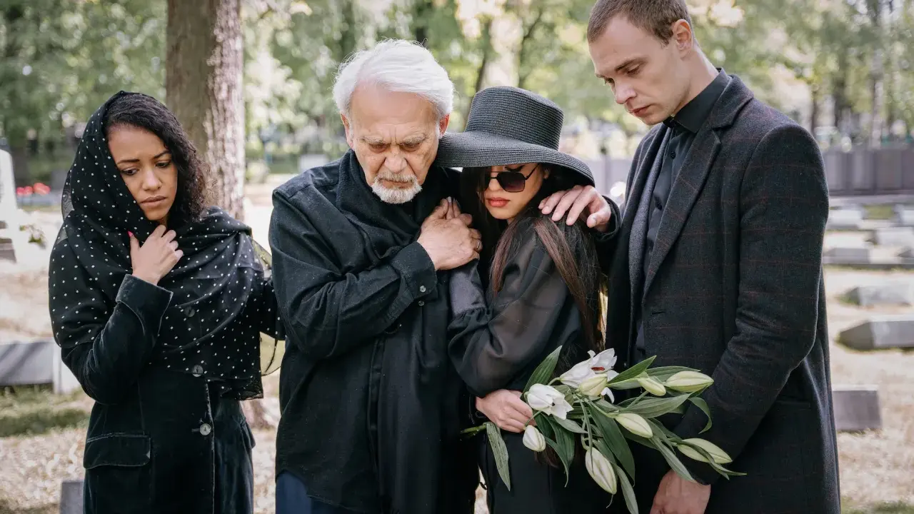 Smutna rodzina w czarnych strojach na cmentarzu. Wskazówki, jak ubrać się na pogrzeb: elegancja i powaga.