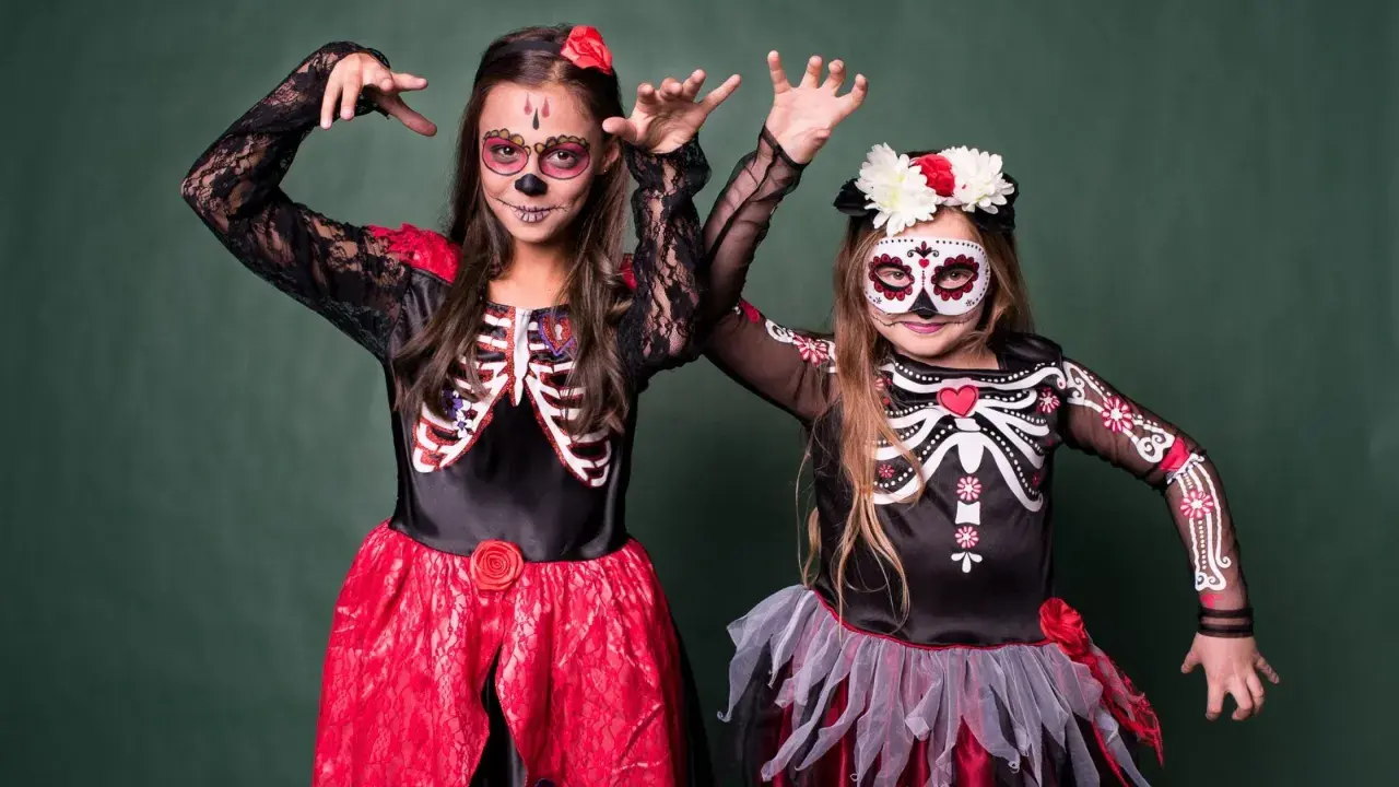 Dwie dziewczynki w strojach szkieletów z makijażem na Dzień Zmarłych. Inspiracja, jak się przebrać na Halloween.