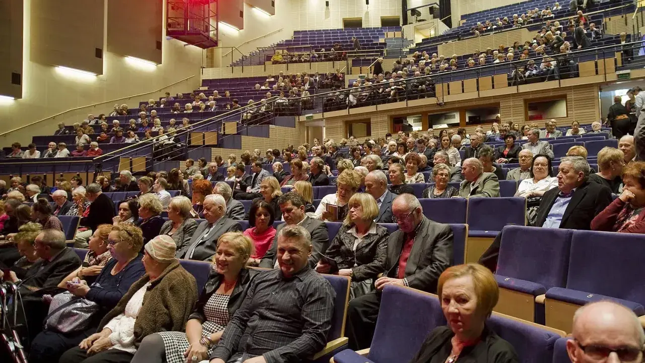 Widownia filharmonii w eleganckich strojach. Zastanawiasz się, jak się ubrać do filharmonii? Tutaj widzisz przykład klasycznych stylizacji.