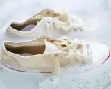 Białe trampki w pianie, z widocznymi żółtymi plamami, czekają na odświeżenie.