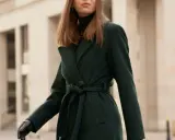 Elegancka kobieta w ciemnozielonym płaszczu z alpaki, z paskiem zawiązanym w talii. Dowiedz się, jak prać płaszcz z alpaki, by zachował swój urok.
