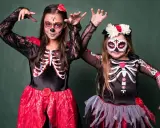 Dwie dziewczynki w strojach szkieletów z makijażem na Dzień Zmarłych. Inspiracja, jak się przebrać na Halloween.