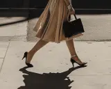Elegancka kobieta w beżowej sukience i czarnej torebce na spacerze. Idealna torebka do beżowej sukienki.