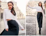 Kobieta w białym sweterku i czarnej satynowej spódnicy, uosobienie stylu minimalistycznego mody, pozuje na tle Wieży Eiffla.