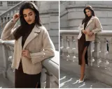 Elegancka kobieta w modnej, beżowej kurtce i brązowej sukience z rozcięciem. Idealna stylizacja na jesień.