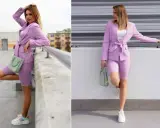 Kobieta w stylizacji w kolorze wrzosowym: marynarka, kolarki i sneakersy. W ręku trzyma miętową torebkę.