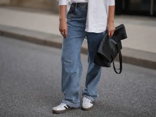 Modne jeansy flare w stylizacji z białą koszulą i czarną torebką.