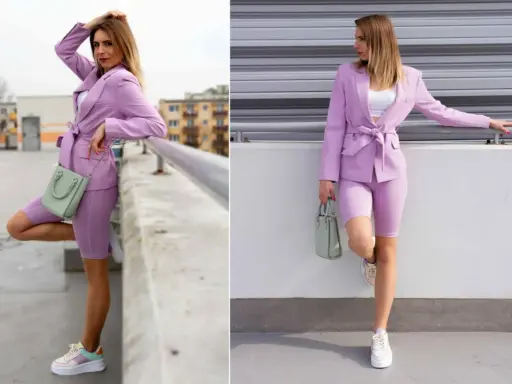 Kobieta w stylizacji w kolorze wrzosowym: marynarka, kolarki i sneakersy. W ręku trzyma miętową torebkę.