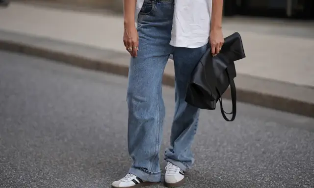 Modne jeansy flare w stylizacji z białą koszulą i czarną torebką.