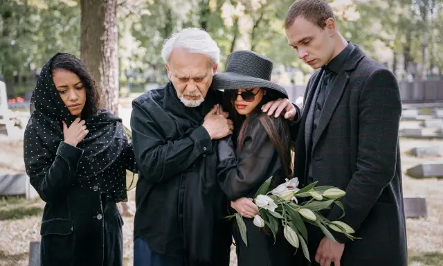 Smutna rodzina w czarnych strojach na cmentarzu. Wskazówki, jak ubrać się na pogrzeb: elegancja i powaga.