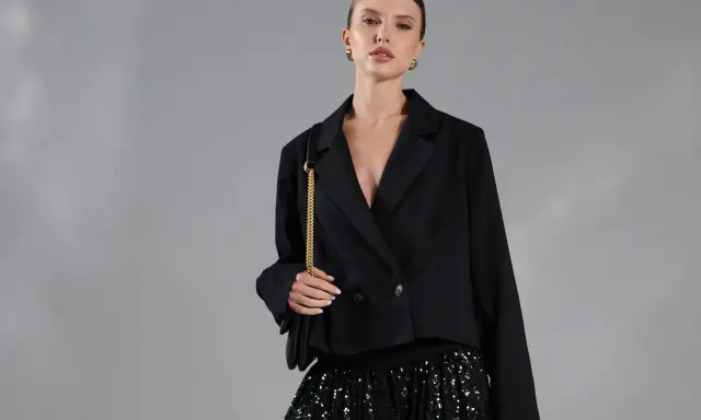 Elegancka kobieta w czarnym żakiecie i błyszczącej spódnicy cekinowej. Stylowe spódnica cekinowa stylizacje na wieczór.