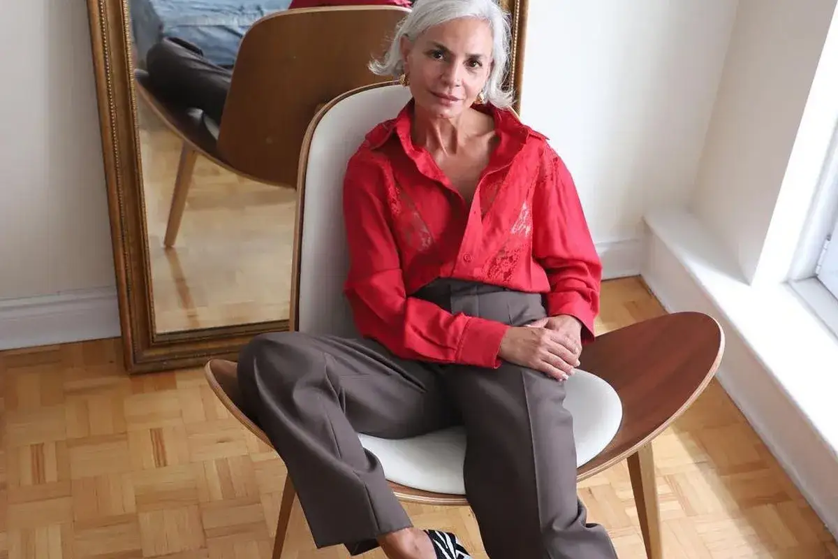 Elegancka 50-latka w czerwonej bluzce i brązowych spodniach. Stylowe zestawy ubrań dla dojrzałych kobiet.