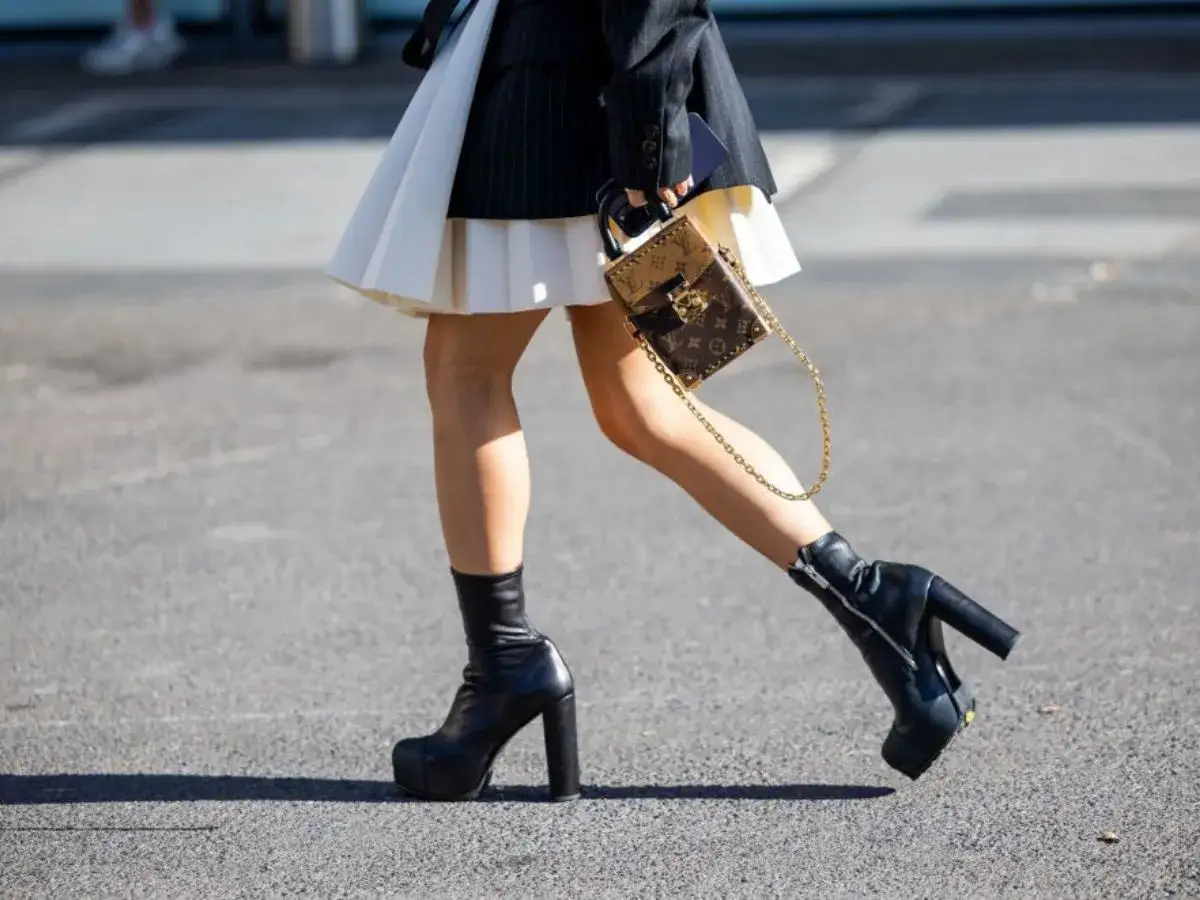Stylowe czarne buty do białej sukienki, dopełnione torebką od Louis Vuitton.